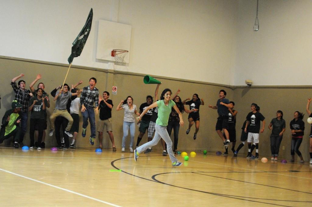 Renu Singh (11) jogs around the dodgeball court after successfully taking out a senior, while her fellow juniors cheer enthusiastically on the sidelines. The class of 2014 defeated the seniors in the dodgeball championship, winning first place.