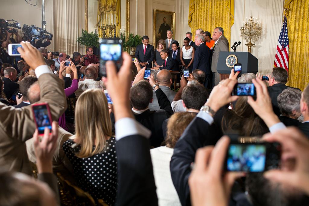 As President Barack Obama signs the Transportation and Student Loan Interest Rate bill on July 6, 2012, guests at the White House take photos. A growing component of election campaigning and news updates, social media was widely used in this year's election.