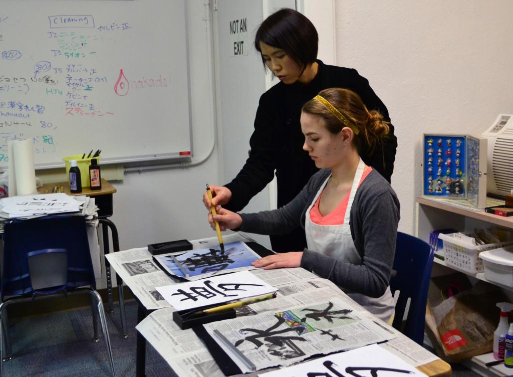 Japanese teacher Masako Onakado guides Sarah Bean (10) by demonstrating the correct brush stroke of writing the character representing dream. In honor of the new year, students participate in kakizome, the first calligraphy activity of the new year.