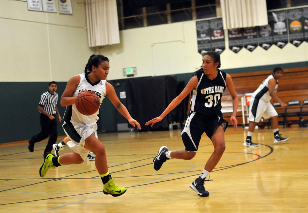 Varsity girls basketball captain Daniza Rodriguez (12) dribbles the ball past an opponent from Notre Dame. The girls were defeated 64-38 by Notre Dame High School on their senior night.