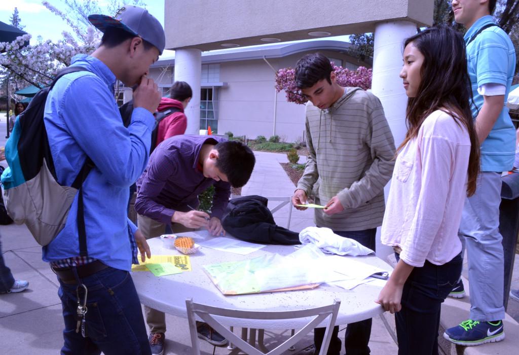 Red Cross club members Sumit Minocha (12) and Jessica Yang (10) give out information about the blood drive as junior Sean Pan signs up to donate. Club members waited with sign-up sheets outside of Manzanita Hall during lunch.