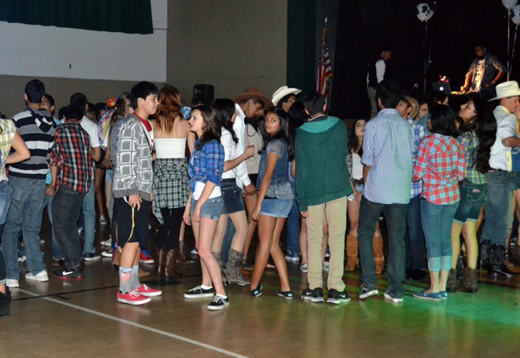 Donned in cowboy hats and denim, students dance to songs played by DJ Bobby Kahlon (12). The Sadies dance took place in the gym on Saturday, March 9.