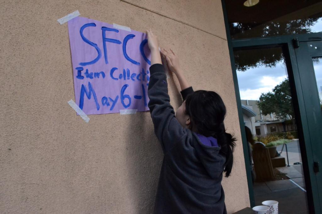 Posting flyers around school, a member of Students For Charitable Causes (SFCC) hopes to raise awareness for the drive. The club planned to work around the school's AP schedule and lack of school meetings.