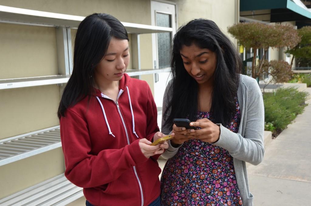 Two students check out their smartphone apps together. Snapchat is the top must-have app.