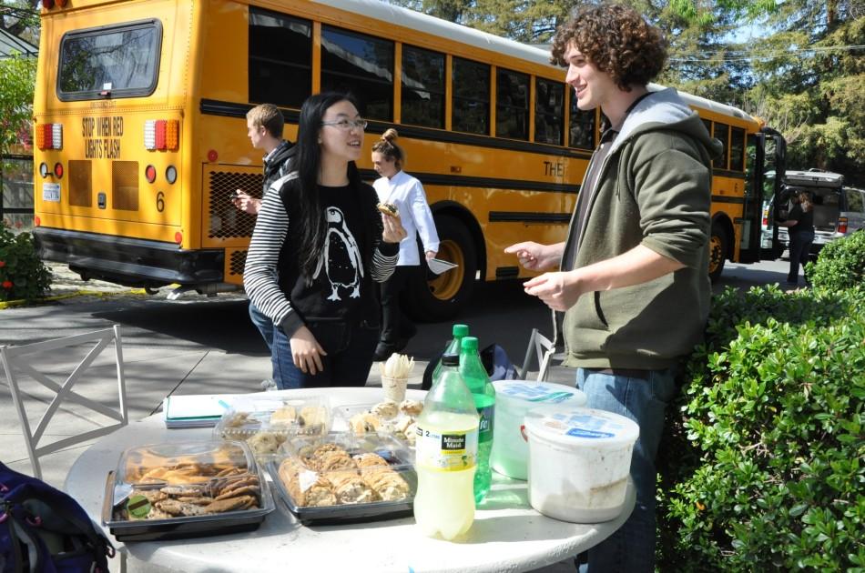 Kacey Fang (11) talks with FEM member Alex Thomas (11) about the fundraiser while enjoying a cookie. Members sold cookies, ice cream, soda, and lemonade after school, and students had the option of either paying in cash or charging to their student accounts.