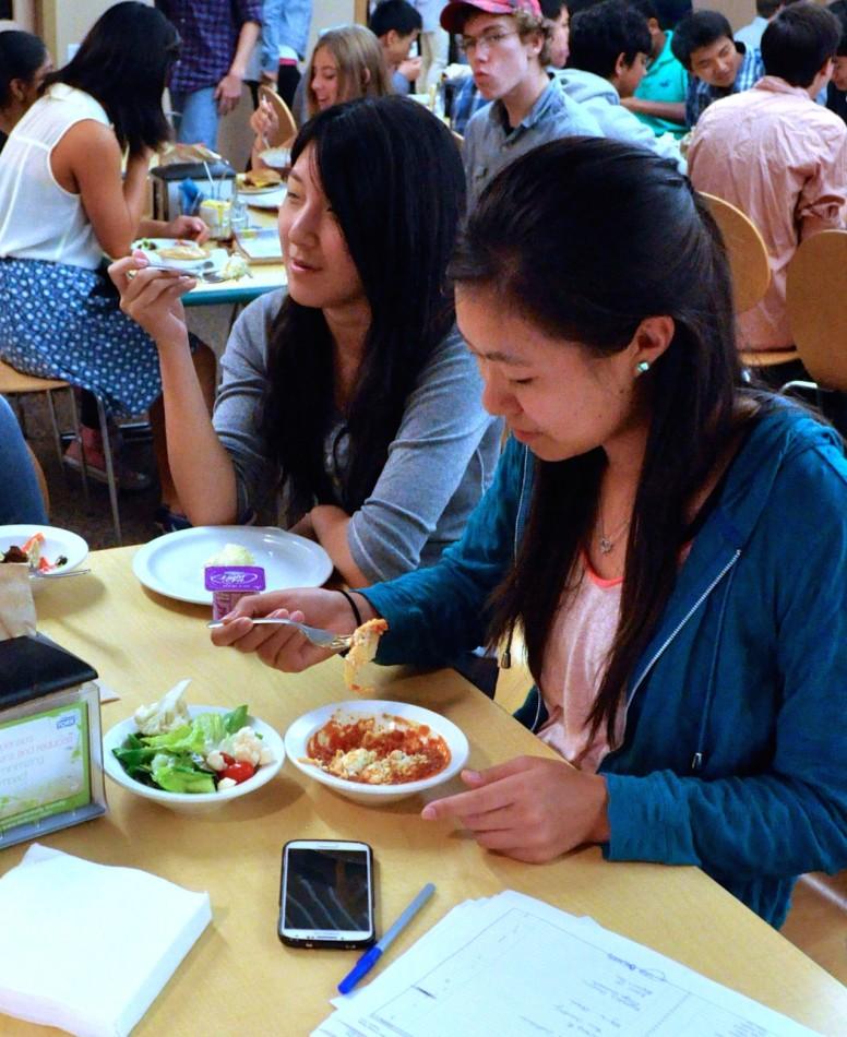 Seniors Dora Tzeng and Elizabeth Teng eat lunch in the bustling Edge. After lunch each day, the kitchen staff evaluates how well the student body cleaned up after itself.