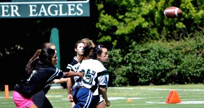 Powderpuff football player on the senior and freshman team throws the ball to a receiving teammate just before the opposing teams members tackles her. The senior and freshman team won 6-0 against the sophomore and junior team.