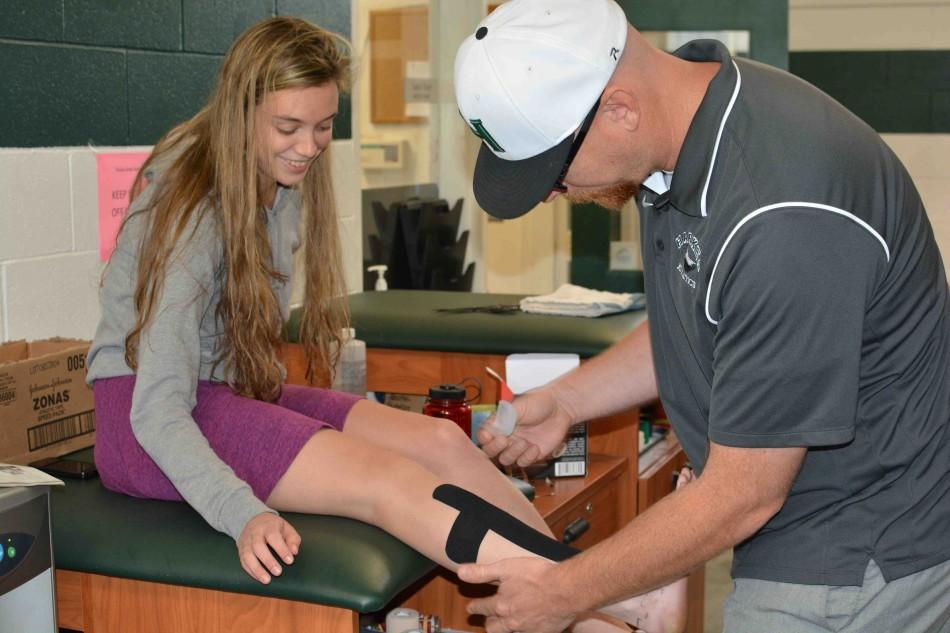 Jaron Olson helps Julia Fink (11) with her strained leg. This, among others skills, will be taught in his sports medicine class next year.