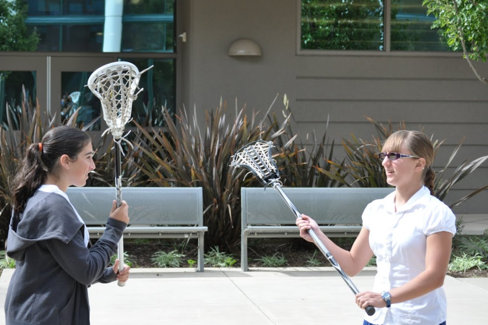 Megan Swanson (9) and Nina Levy (9) hold up their lacrosse sticks in preparation for a Stick-Five. The Stick-Five is a high-five with the lacrosse sticks, to get pumped up for the games.