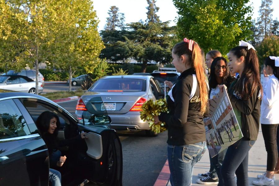 Elizabeth Edwards (11) greets an incoming student as she and other athletes hold signs and wave pom-poms during the Curbside Crazy Event. The event is held to help support the construction of the new Events center.