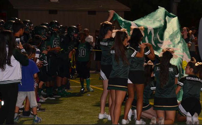 The cheerleaders hold a banner before the varsity football team enter onto Davis field.