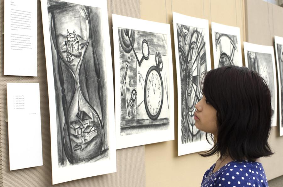 	Kaity Gee (11) contemplates Cheryl Liu’s collection of drawings titled “Deconstruction.” Cheryl was among 23 students featured in the APSA exhibit during long lunch in Nichols Hall.