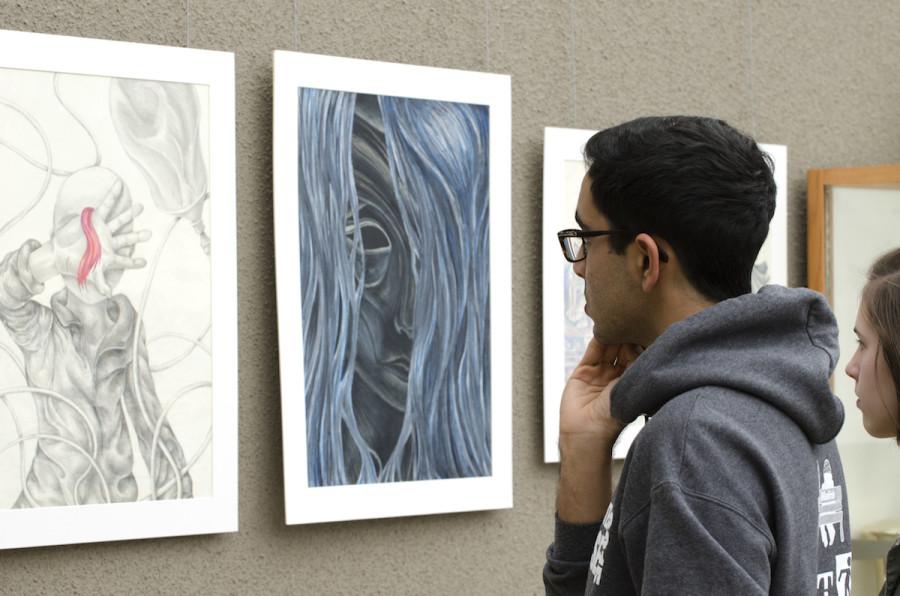 Jai Ahuja (12) and Helen Woodruff (11) study the untitled drawing collection of Sophia Luo (11) during the APSA exhibit. The exhibit featured works from 23 artists.