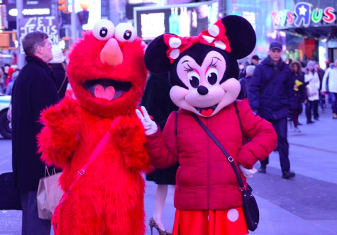 Characters dressed as Elmo and Minnie Mouse move around Times Square. Their goal is to take pictures with tourists to earn tips.