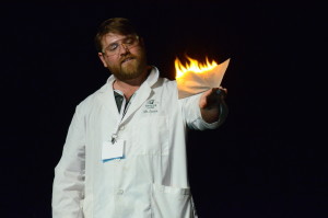 Chemistry teacher Andrew Irvine holds a burning tissue in his hand. The upper school chemistry department worked together to perform their annual magic show at the symposium.