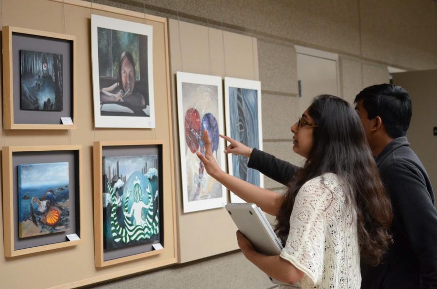 Ishanya Anthapur (12) and Rahul Jayaraman (12) examine a piece of art hanging on the wall during the Artstravaganza exhibit in Nichols. The Artstravaganza le Deuxième was held yesterday during long lunch in the Nichols Atrium.