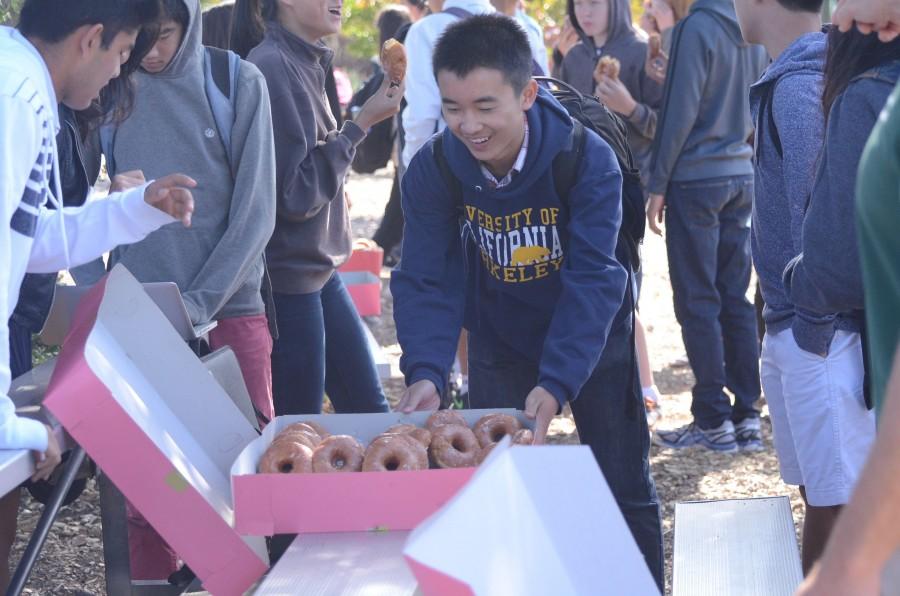 Jimmy Lin (9) sets down a box of fresh donuts on the Rosenthal field bleachers after third period. As the freshmen class president, Jimmy helped organize the event.
