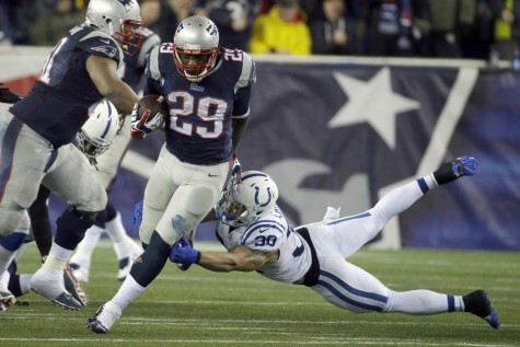 A player from the Patriots runs with the ball, attempting to avoid the defensive player from the Colts. The 2015 AFC Championship between the two teams resulted in the Deflategate controversy.