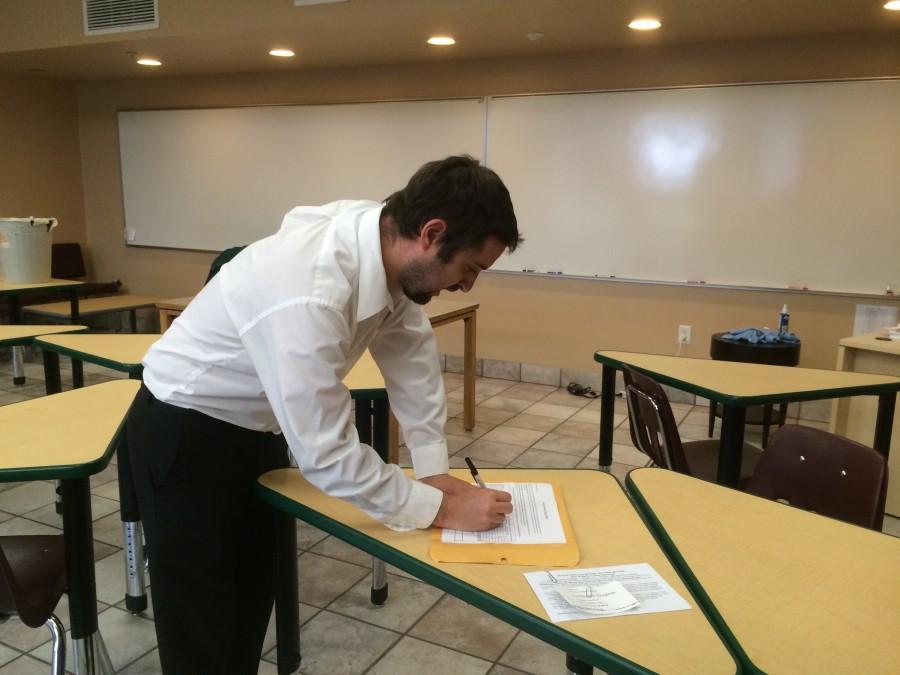 Lepler signs forms during advisory. The changes with Economics and the Business and entrepreneurship department affected the location of his room.