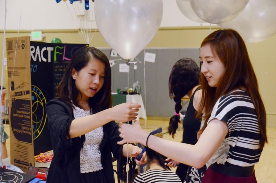 Interact Co-Presidents Alice Wu (12) and Kevina Xiao (12) cut a balloon for their booth during Club Fair. The annual Club Fair helped clubs attract new members.