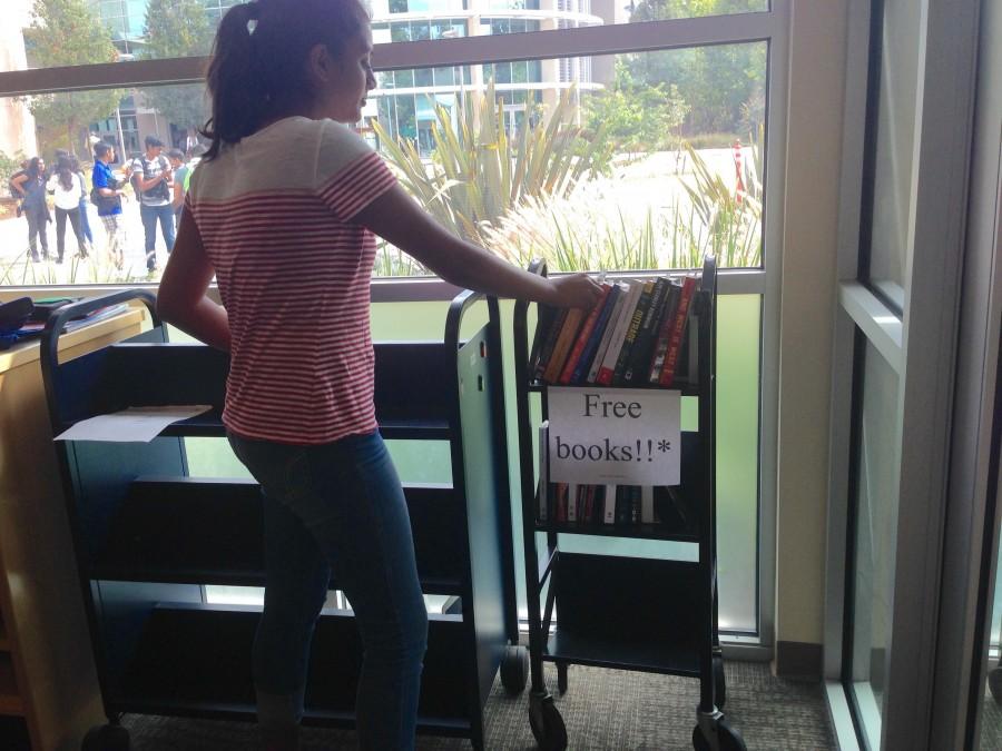 Chetana Kalidindi (11) examines the book cart. Students can write a review of the book on the Book Blog. 