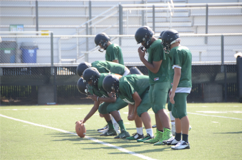 The football team practices running plays during their summer practices.