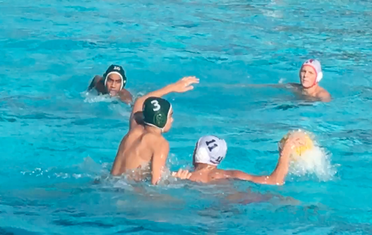 Two Harker team members try to prevent a Saratoga player from passing the ball as one of his teammates swims towards them.