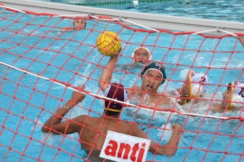 Edward Sheu (12) shoots the ball into the goal while there are two defenders and a goalie trying to stop him. The boys won 20-5.