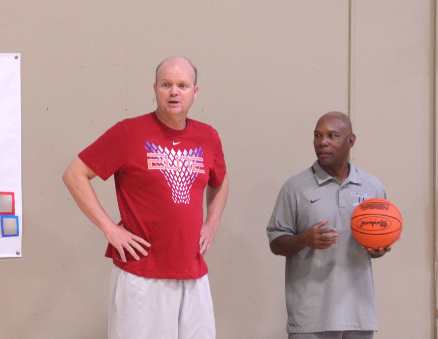 Coaches Thompson and Pringle watch the players sprint to warm up before beginning to practice at an open gym as the latter handles a basketball. The coaches want mostly to build up [the players] fundamentals, skill development and a winning attitude, Pringle said.