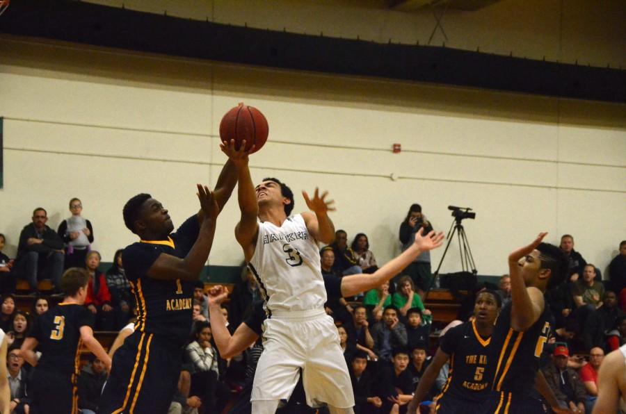 Elijah Edgehill (12) leaps with the ball towards the basket as opposing defenders surround him. The boys' victory against King's Academy yesterday brings the team to a 3-5 league record and an 11-7 overall record.