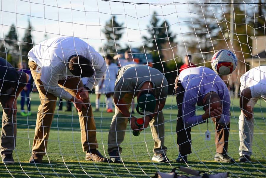 Teachers line up against the goal as kids kick soccer ball as them in the Butts Up game.