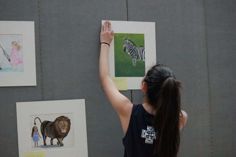 Madison Tomihiro (12) hangs up one of her pieces that she drew for her portfolio. The exhibition featured art works from a total of 25 students taking the AP course.
