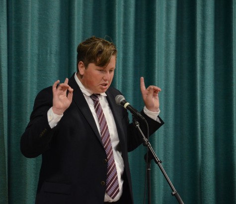 MC Logan Dragovich (12) makes exaggerated motions as he plays the role of "Tronald Dump" in a parody of a Republican debate performed between acts. The other three MCs participating in the skit portrayed "Jobby Bindal," Ben Carson and the debate moderator.