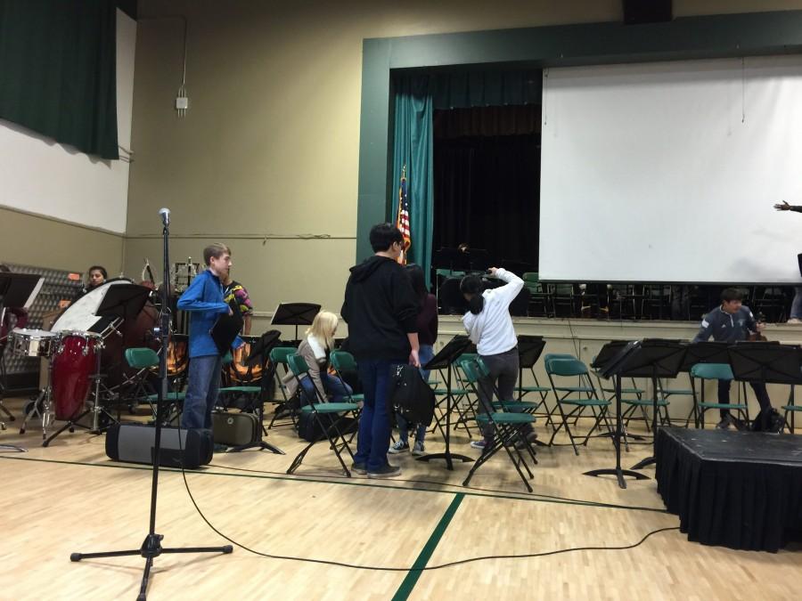 Caption: Orchestra members set up their instruments and stands in preparation of their performance during the meeting. The orchestra will play in its spring concert this Friday at De Anza College.
