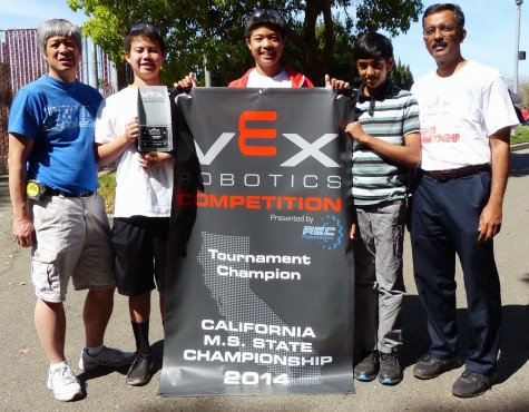 Christopher, Andrew and Kaushik pose with two of their mentors and a their banner award from the 2014 California Middle School Championships, where they became tournament champions in the seventh grade.