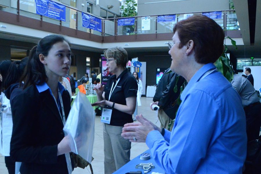 Amy Dunphy (10), one of the Synopsys grand prize winners, speaks with a booth presenter at Symposium.