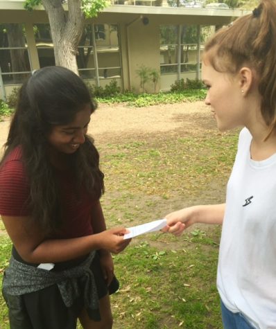 Freshmen Taylor Vaughan offers a poem to Anusha Kuppahally (9) on Poem in Your Pocket Day. “Poems like these are so short and easy to share,” Taylor said. “You can just look at them whenever you’re having a bad day, and I think that’s really nice.” 