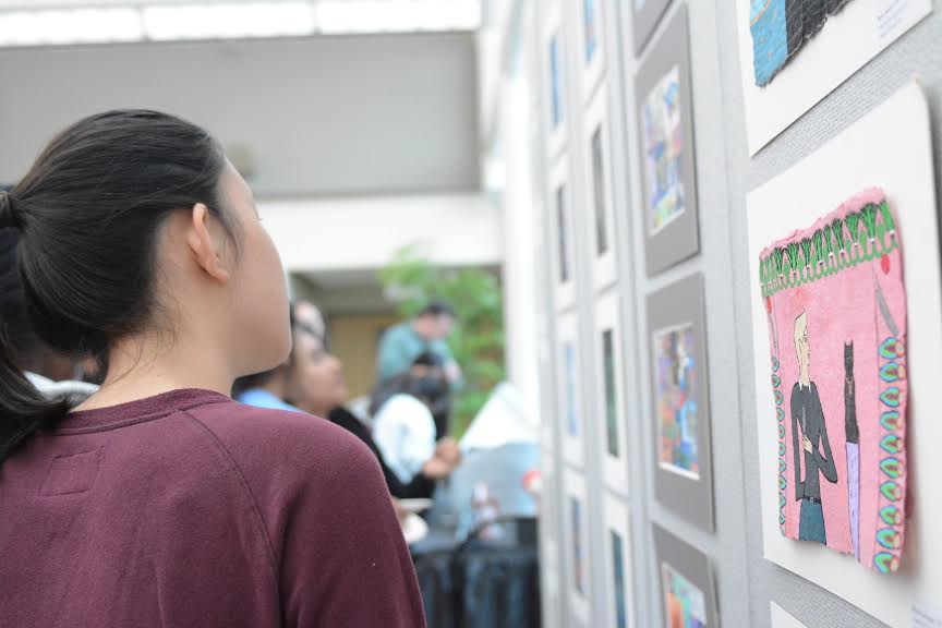 Annie Zhou (12) looks at artwork during the event. The Artstravaganza was held in Nichols during long lunch on Wednesday.