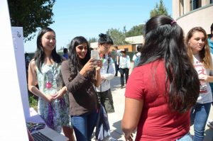 Aliesa Bahri (11) and Millie Lin (11) take a picture of Anusha Kuppahally (10) for FEM Club. The annual Club Fair took place on September 6.
