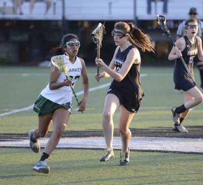 Junior Anuva Mittal runs with the ball as she tries to get past a Mitty defender during the first lacrosse match of last season. Alyssa Dunlap became head coach of the girls team for the upcoming spring season.