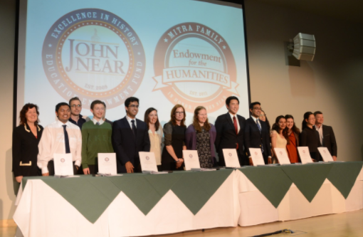 This year's nine Near and Mitra scholars pose with their writing mentors for pictures behind a table of their completed papers. The banquet honoring the scholars took place in the Nichols Auditorium.