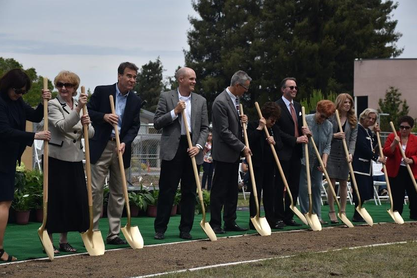 Board of Trustees and administration members use golden shovels to dig up soil on Rosenthal Field during the campus May 2016 groundbreaking ceremony. Previous Head of School Chris Nikoloff opened the event with introductory remarks before welcoming Head of the Board of Trustees Diana Nichols.