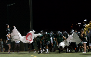 The varsity football team breaks through the poster after halftime. The team is still undefeated after their win against Lindhurst.