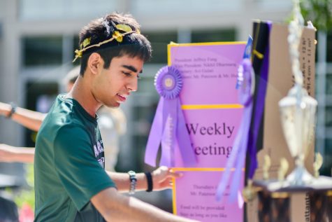 Avi Gulati (11) adjusts Junior Classical Leagues poster board at Club Fair.