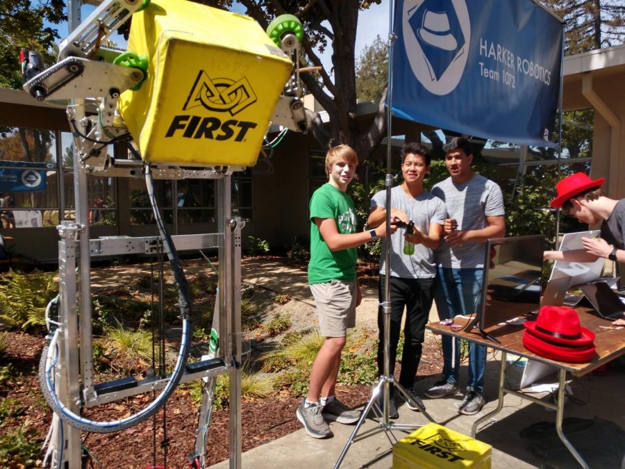 Finn Frankis (11) and Puneet Nayyar (12) help Andrew Chang (12) control Harker Robotics's robot at its booth at Club Fair.