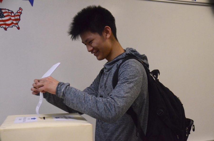 Alexander Young (12) shakes his ballot into a ballot box during the mock midterms last Thursday. AP U.S. Government teacher Carol Green and students hosted a mock midterm election Thursday to encourage students to vote.