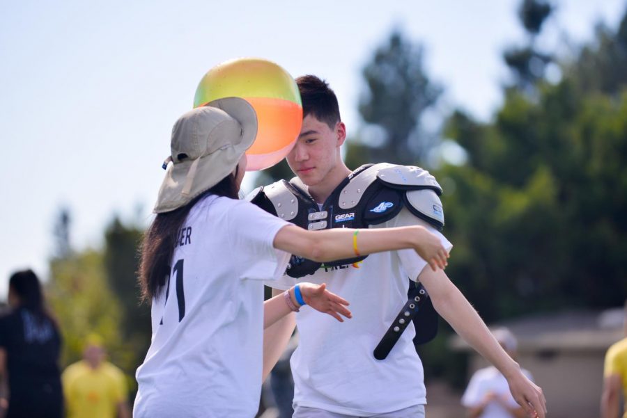 Sophomore homecoming court representatives Alex Zhai and Vivian Jin balance a beach ball between their foreheads during the relay race, which concluded the spirit rally.