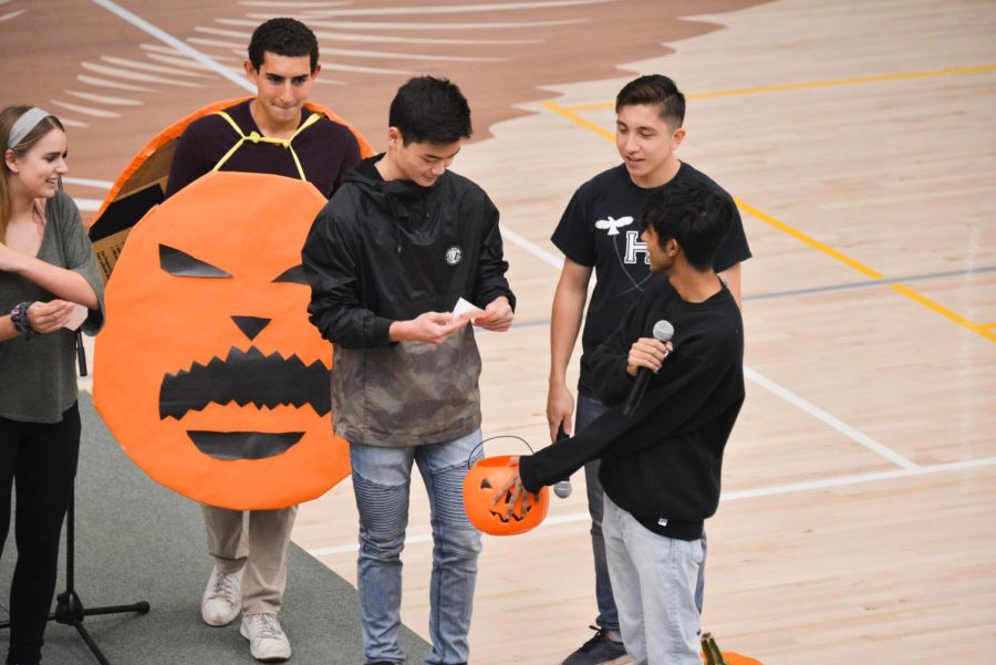 Junior spirit representative Vance Hirota (10) picks a number from a basket to draw for a pumpkin in preparation for a pumpkin carving competition later this week.