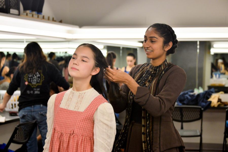 Vaishnavi Murari (10), who plays Woman in Back of Auditorium, ties back Maya Franz (10)'s hair. In this year's fall play, "Our Town", Maya plays Rebecca Gibbs, the sister of George Gibbs.