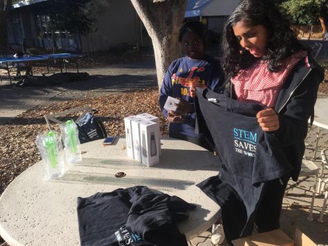 Suman Mohanty (10) holds up a STEM saves the worldt-shirt at the WiSTEM club week booth outside Manzanita. WiSTEM had  speakers, a movie screening, and fundraisers for education for girls in Kenya during its club week.
